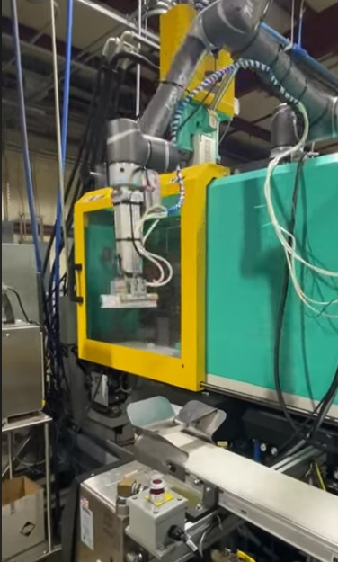 Gray cobot lowering a part held by suction